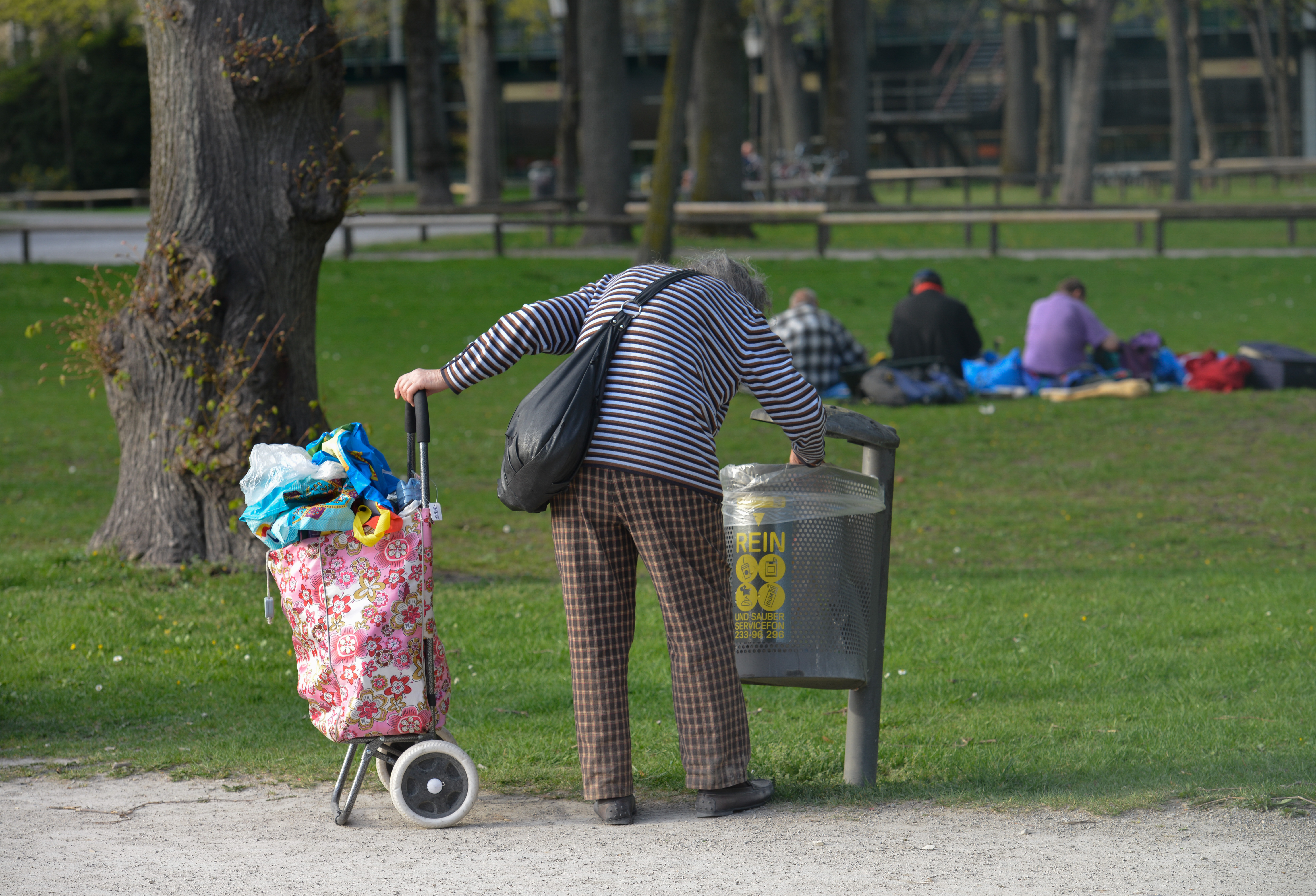 Eine Frau, die im Müll nach Pfandflaschen sucht.