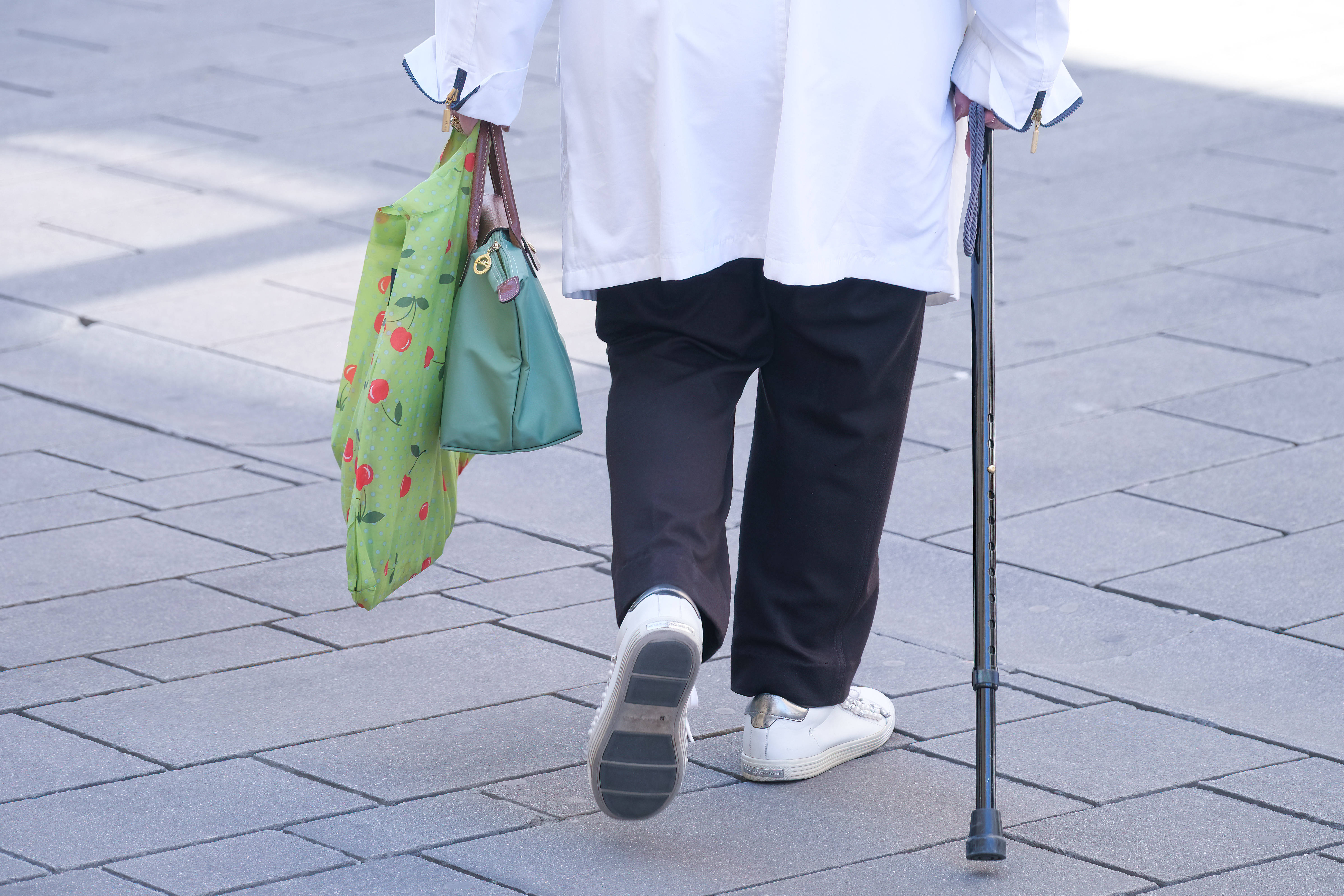 Eine Rentnerin läuft durch eine Einkaufsstraße
