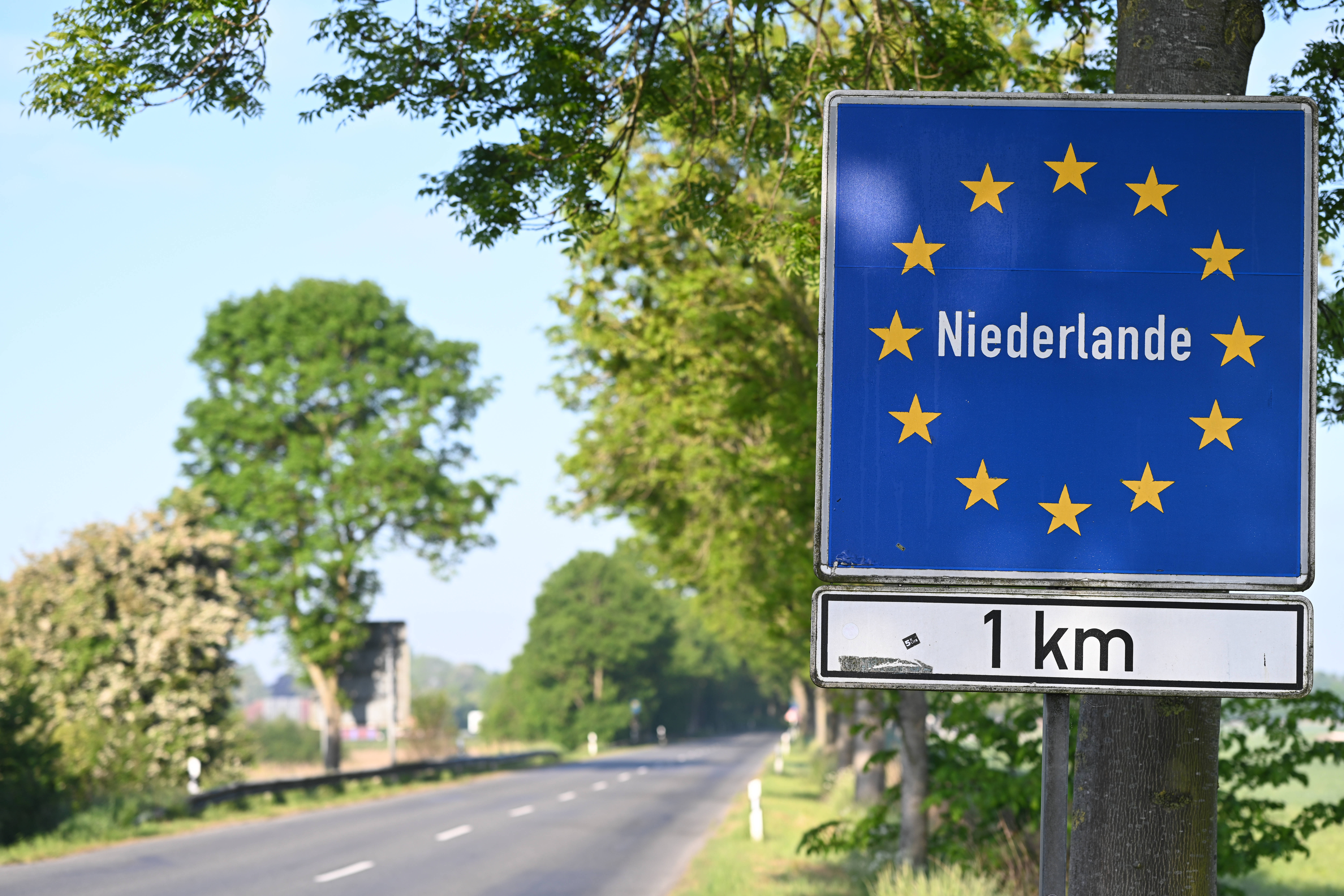 Schild an einer Straße zur Ankündigung der niederländischen Grenze in einem Kilometer Entfernung