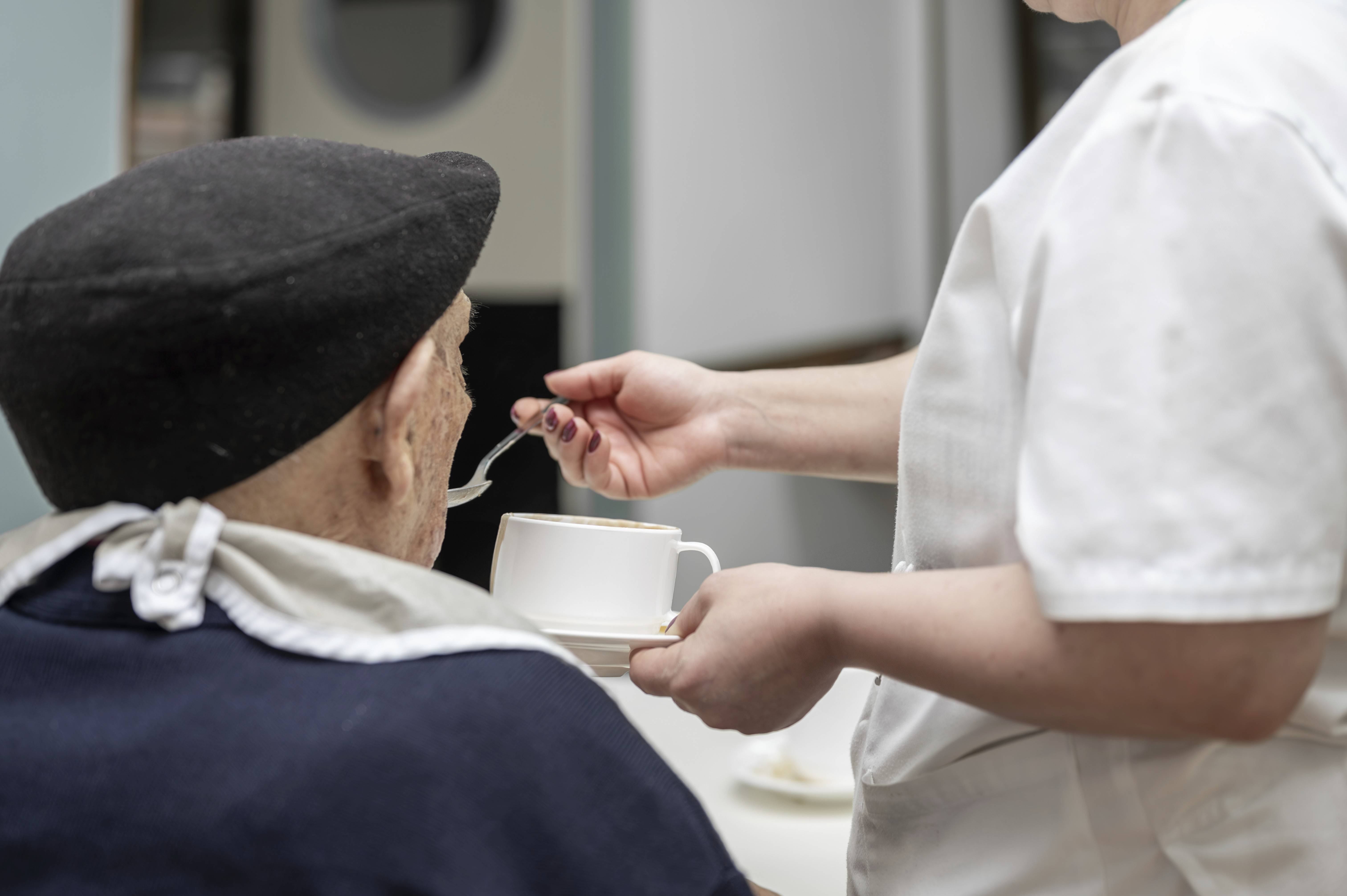 Eine Pflegekraft versorgt einen Heimbewohner