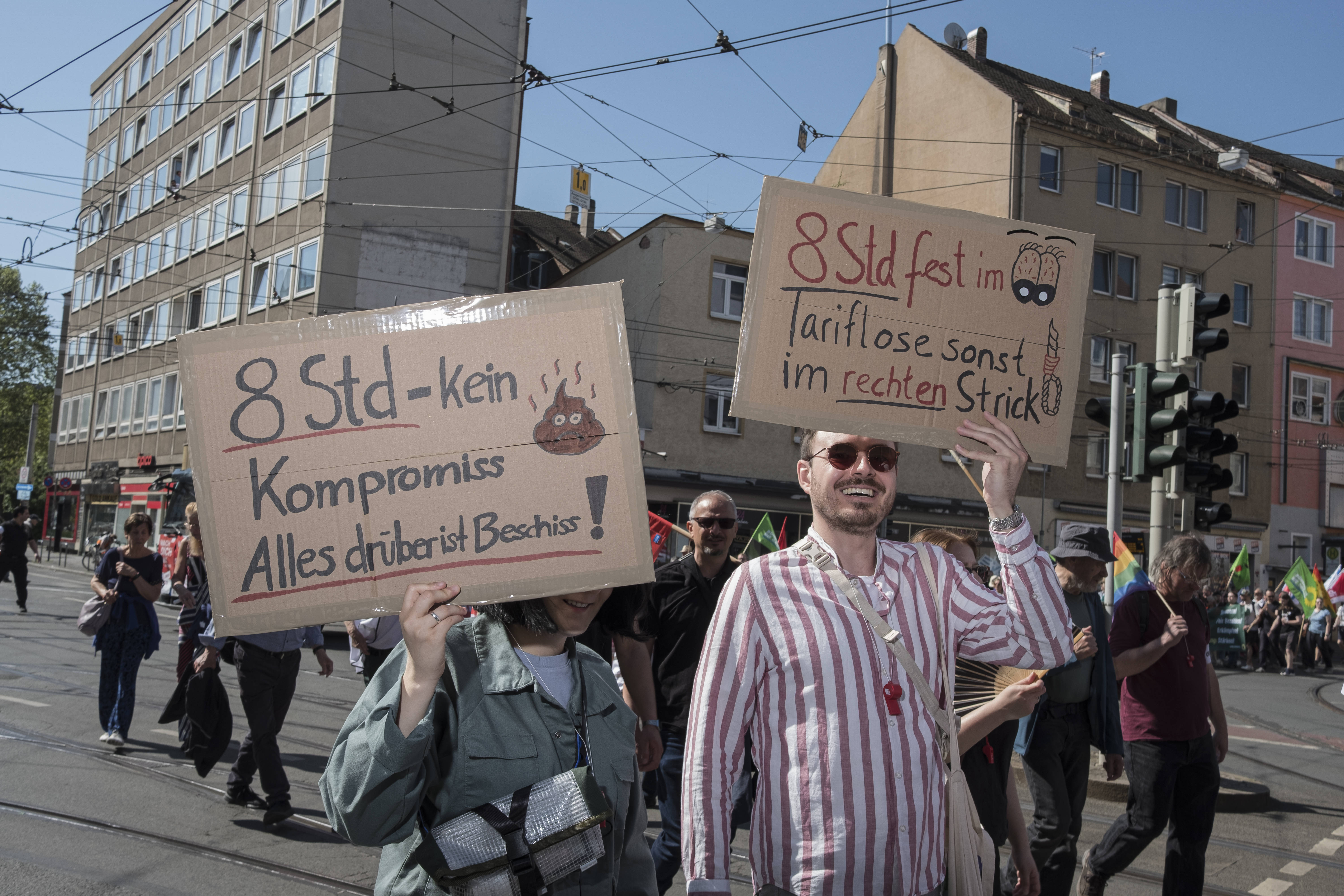 Bei der DGB-Demo zum 1. Mai in Nürnberg demonstrieren Menschen mit selbst gebastelten Pappschildern gegen die geplante Ausweitung des 8-Stunden-Tages.