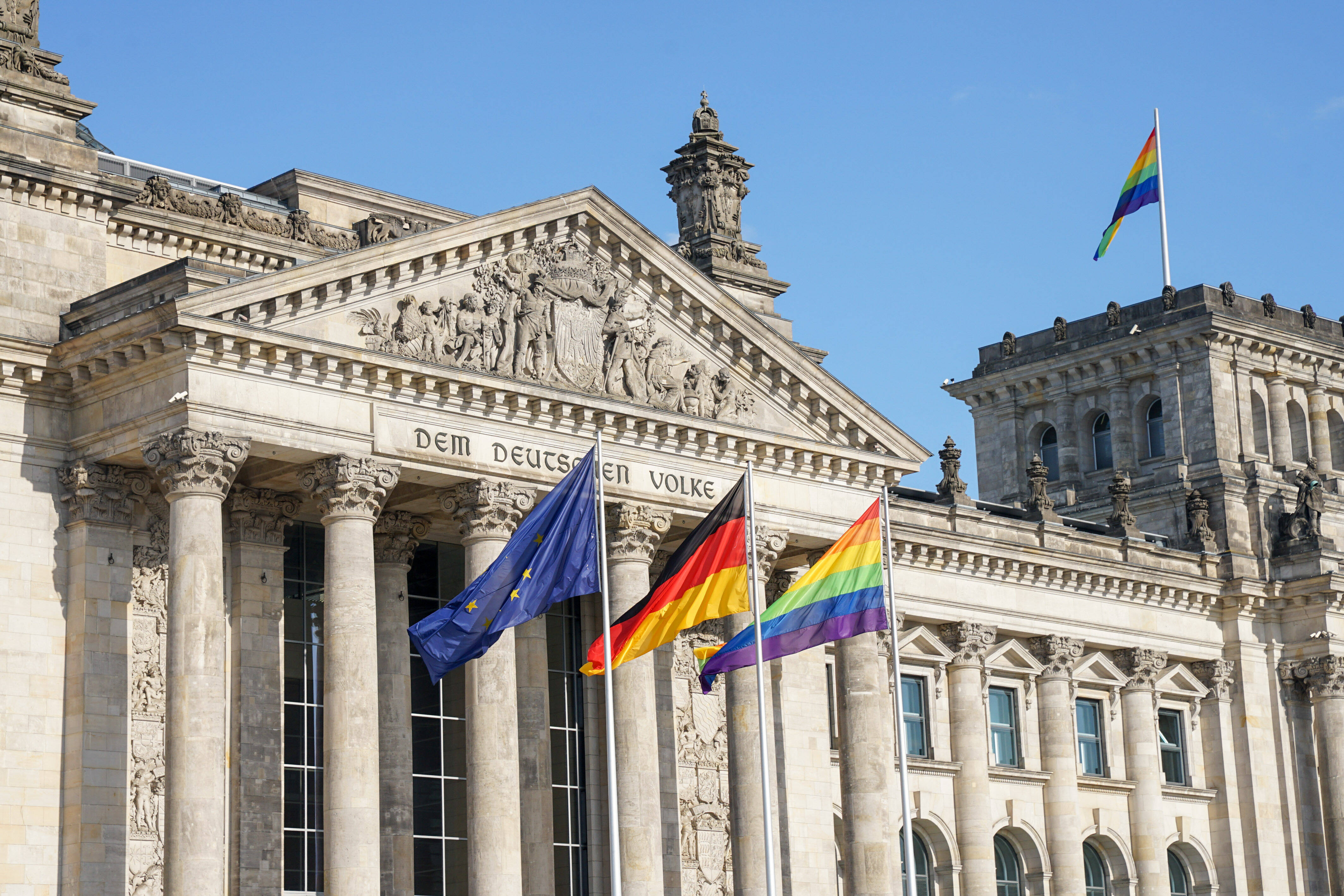 Europa-, Deutschland- und Regenbogenflagge vor dem Reichstagsgebäude in Berlin