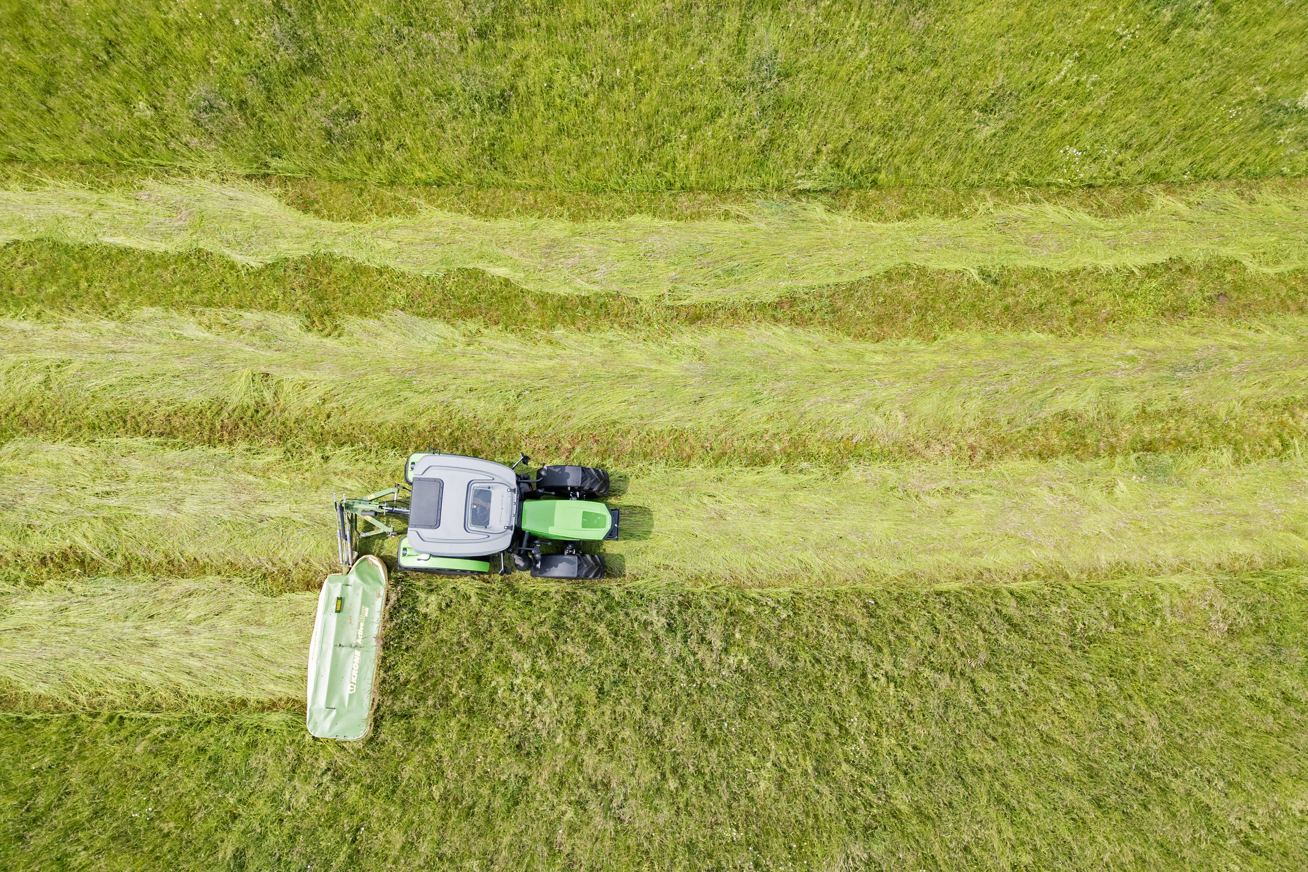 Luftaufnahme eines Traktors beim Mähen einer Grasfläche