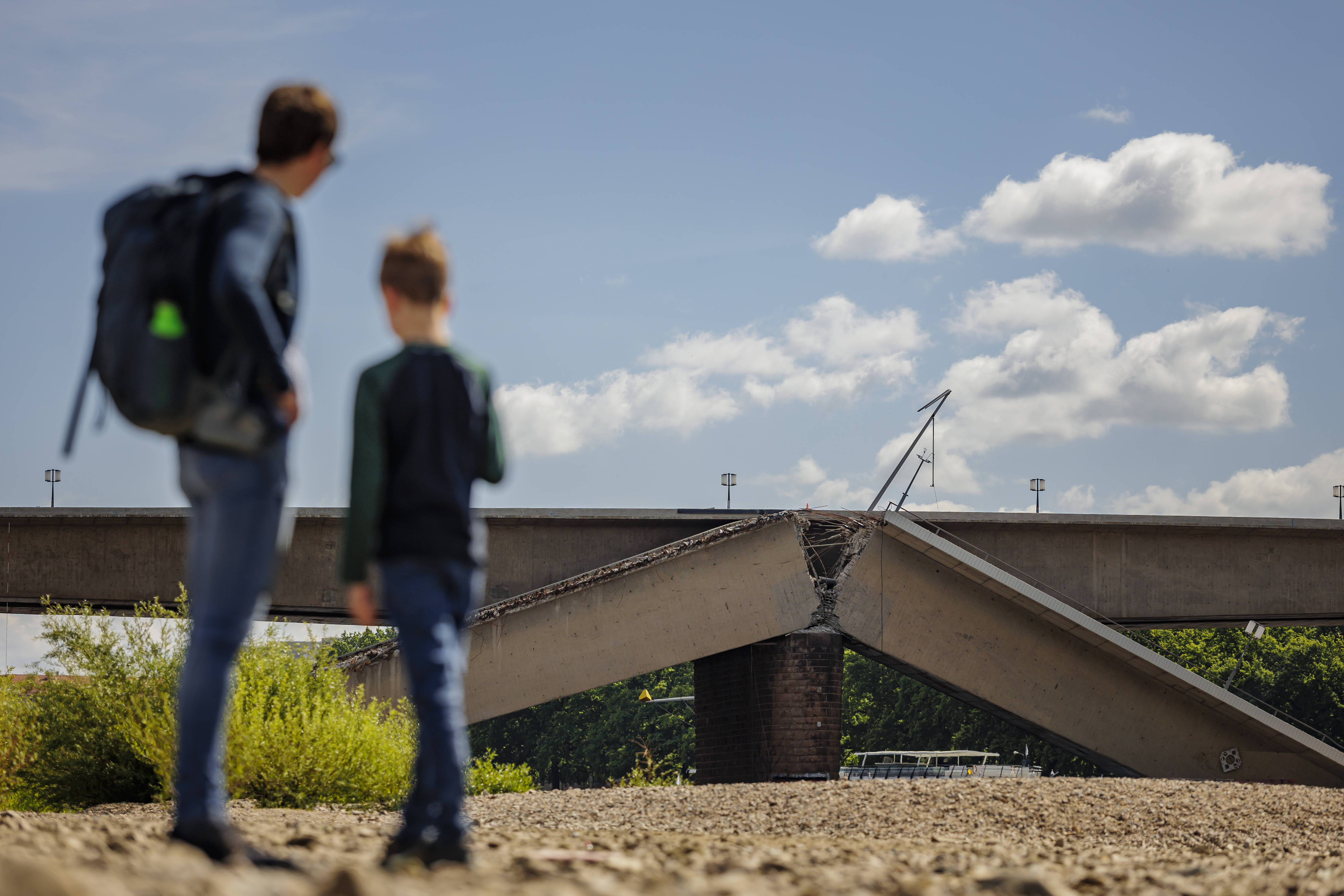 Eingestürzte Carolabrücke in Dresden, im Vordergrund links unscharf ein Mann und ein Junge
