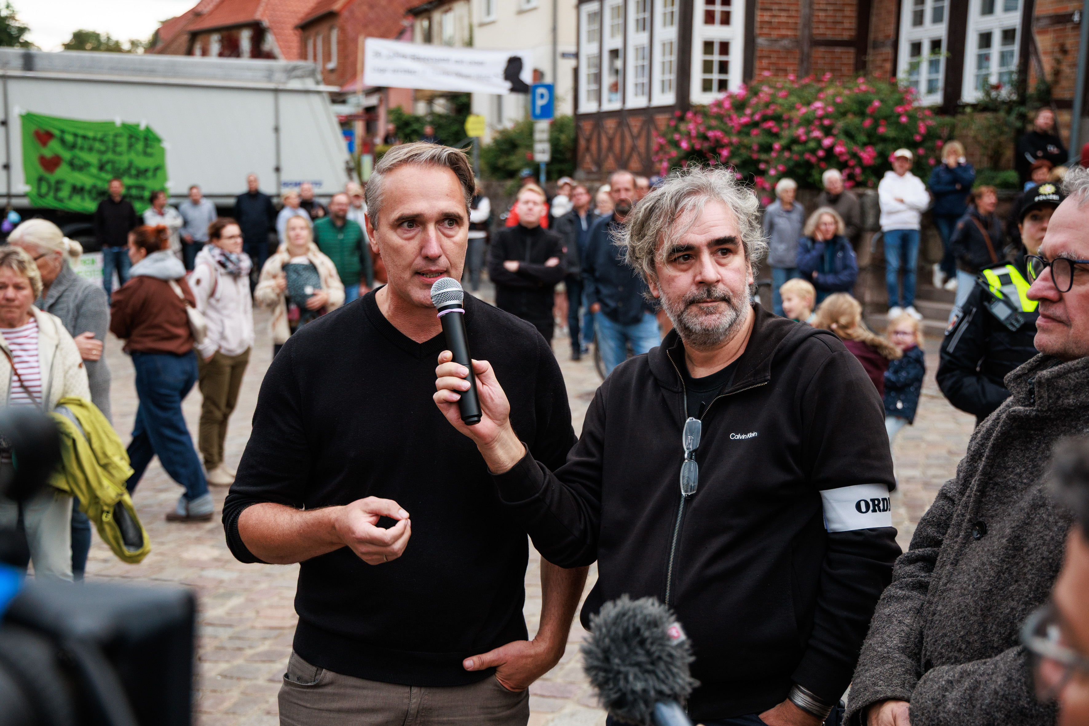 Ein Mann spricht in ein Mikrofon, das ein anderer Mann hält.