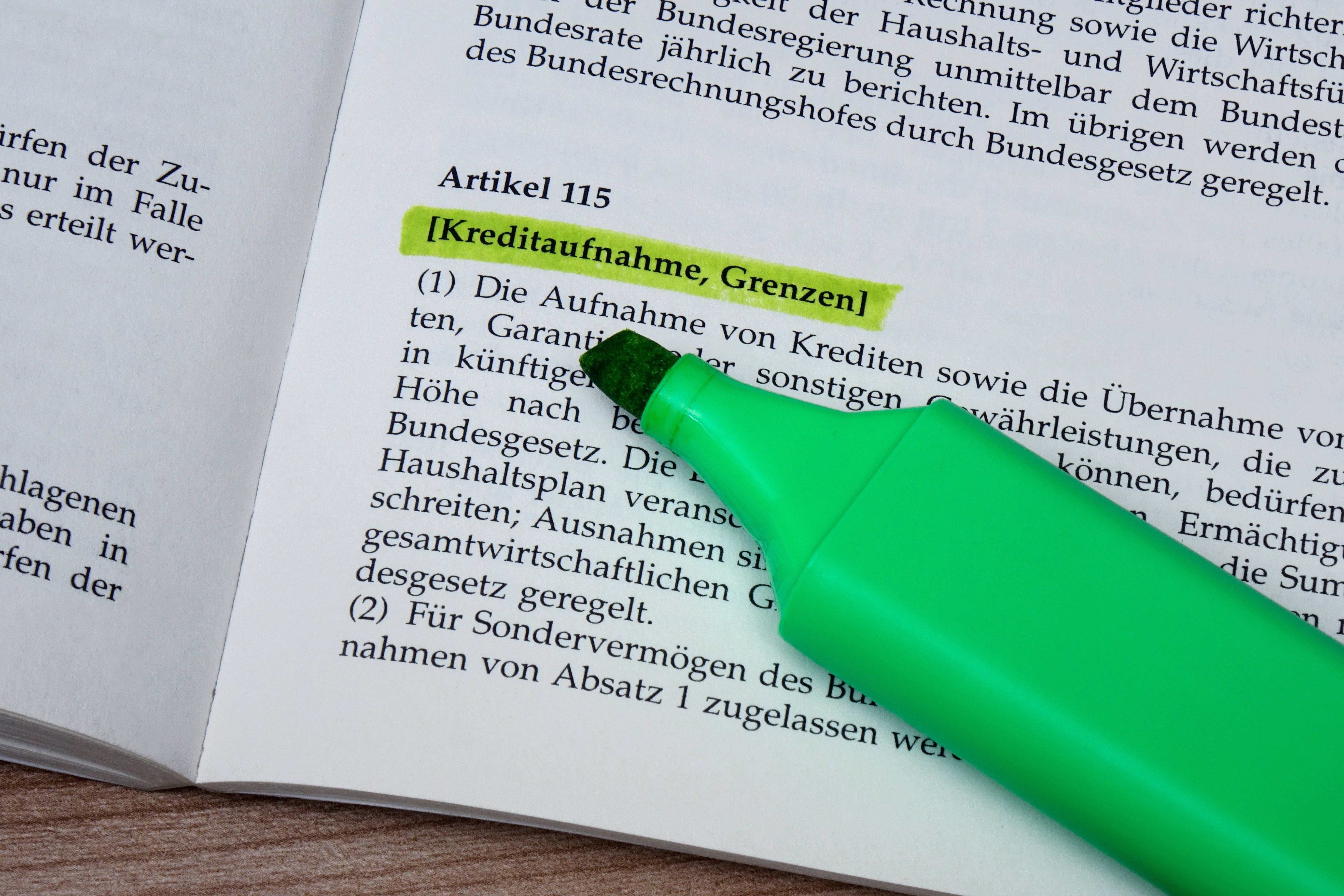 Ein grüner Textmarker liegt auf einer aufgeschlagenen Seite des Grundgesetzes mit Artikel 115.
