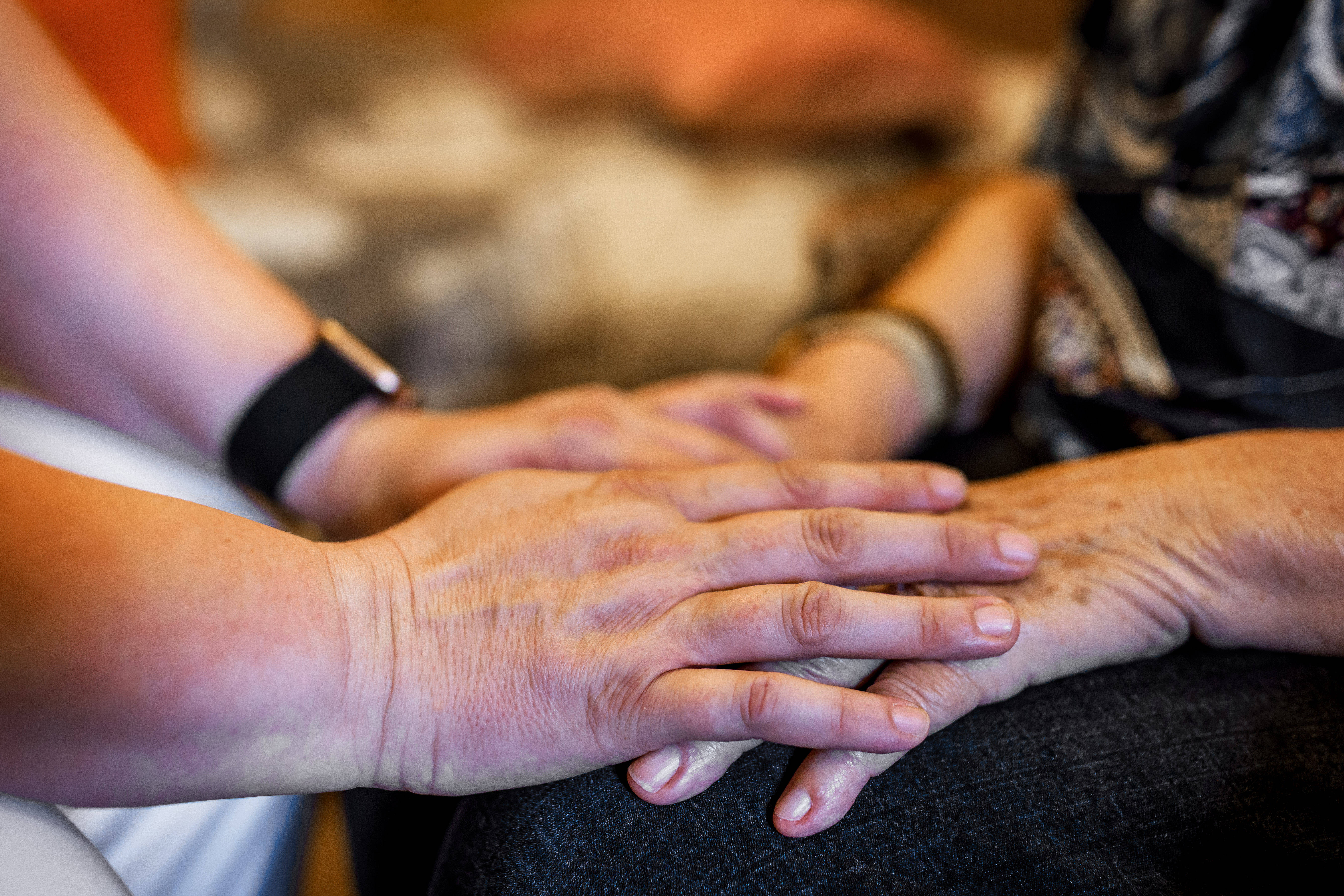 Eine Pflegefachkraft hält die Hand eines Pflegeheimbewohners