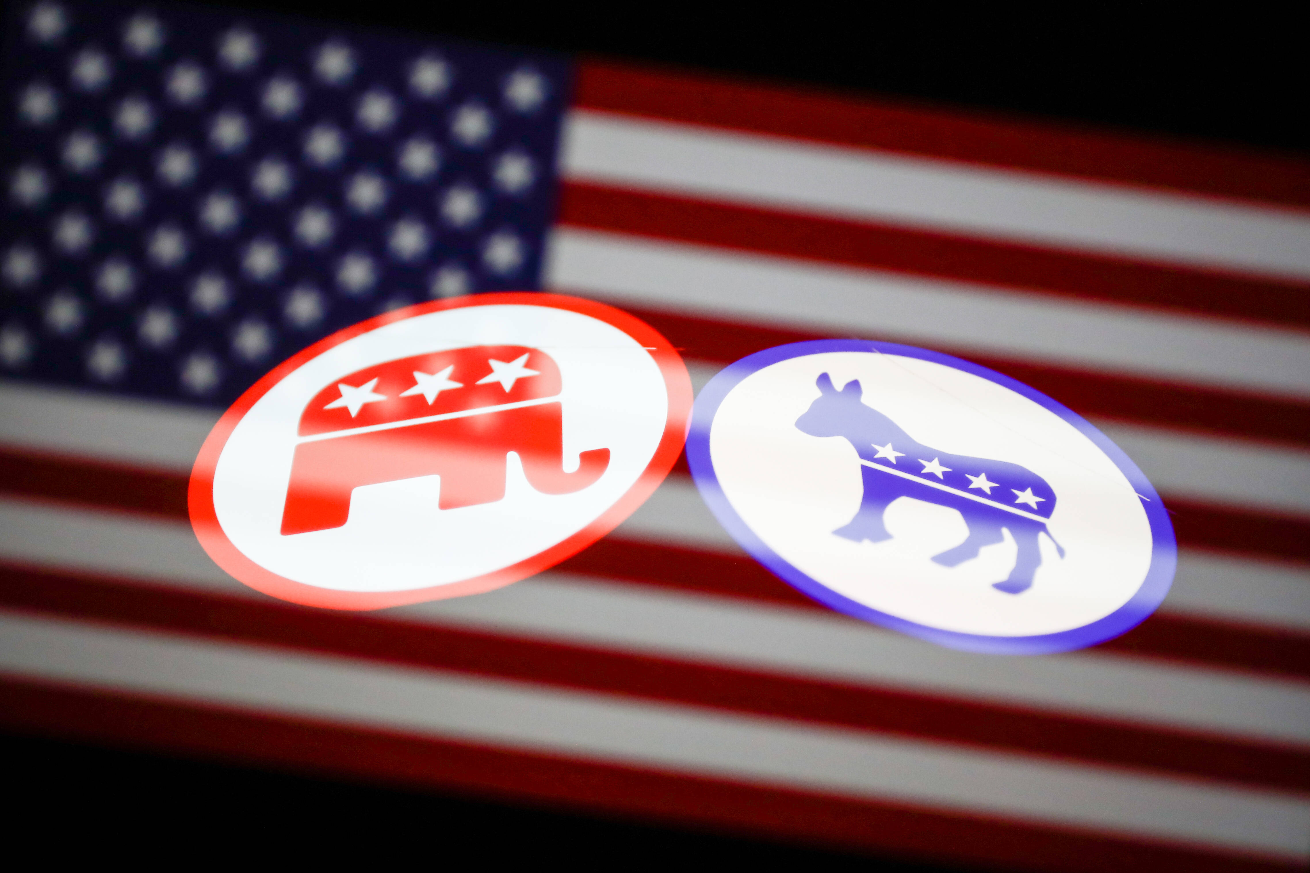 Das Logo der US-Republikaner und das Logo der US-Demokraten vor der amerikanischen Flagge