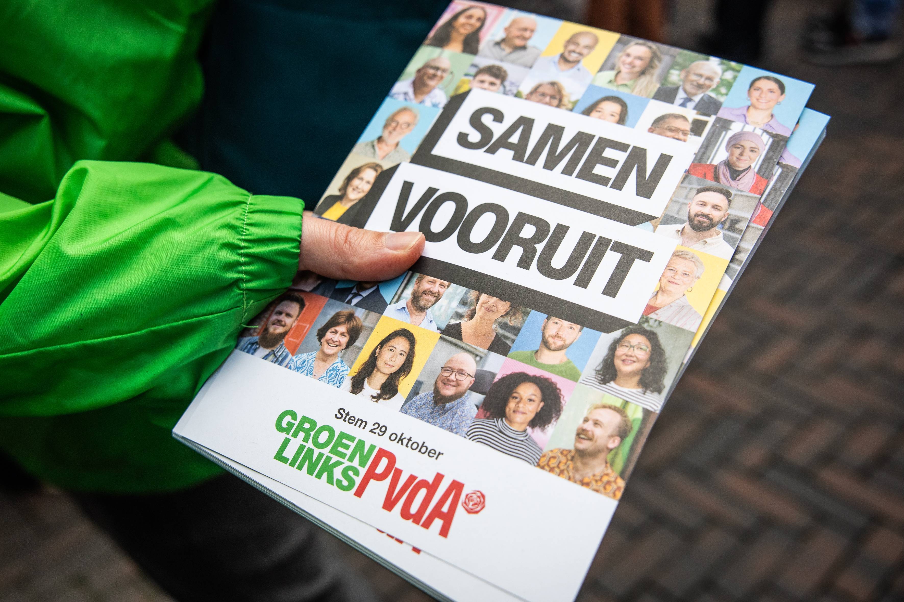 Gemeinsamer Wahlflyer von PvdA und GroenLink mit vielen Porträt, gehalten von einer Hand im grünen Ärmel