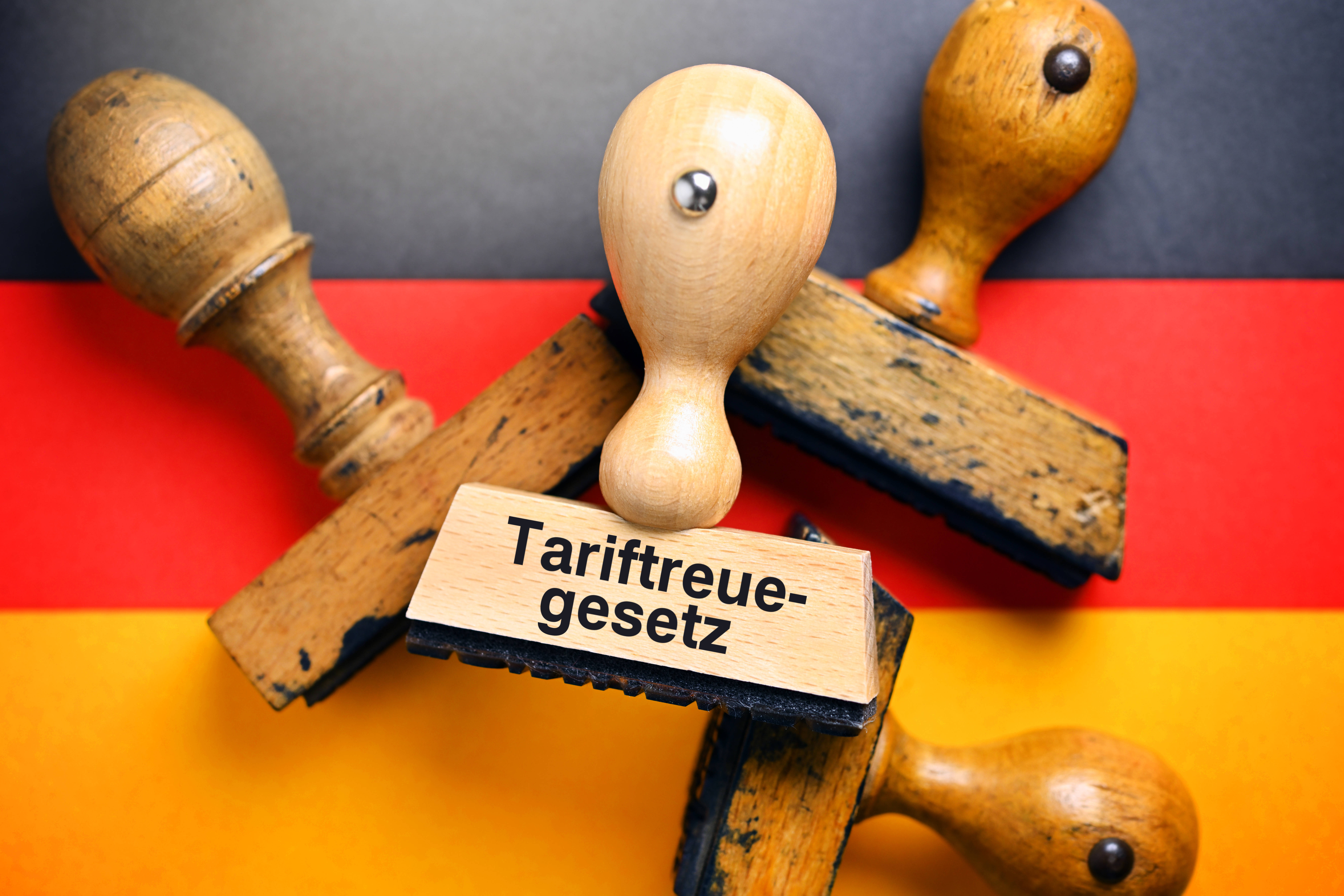 Ein Stempel mit der Aufschrift Tariftreuegesetz auf einer Deutschlandfahne
