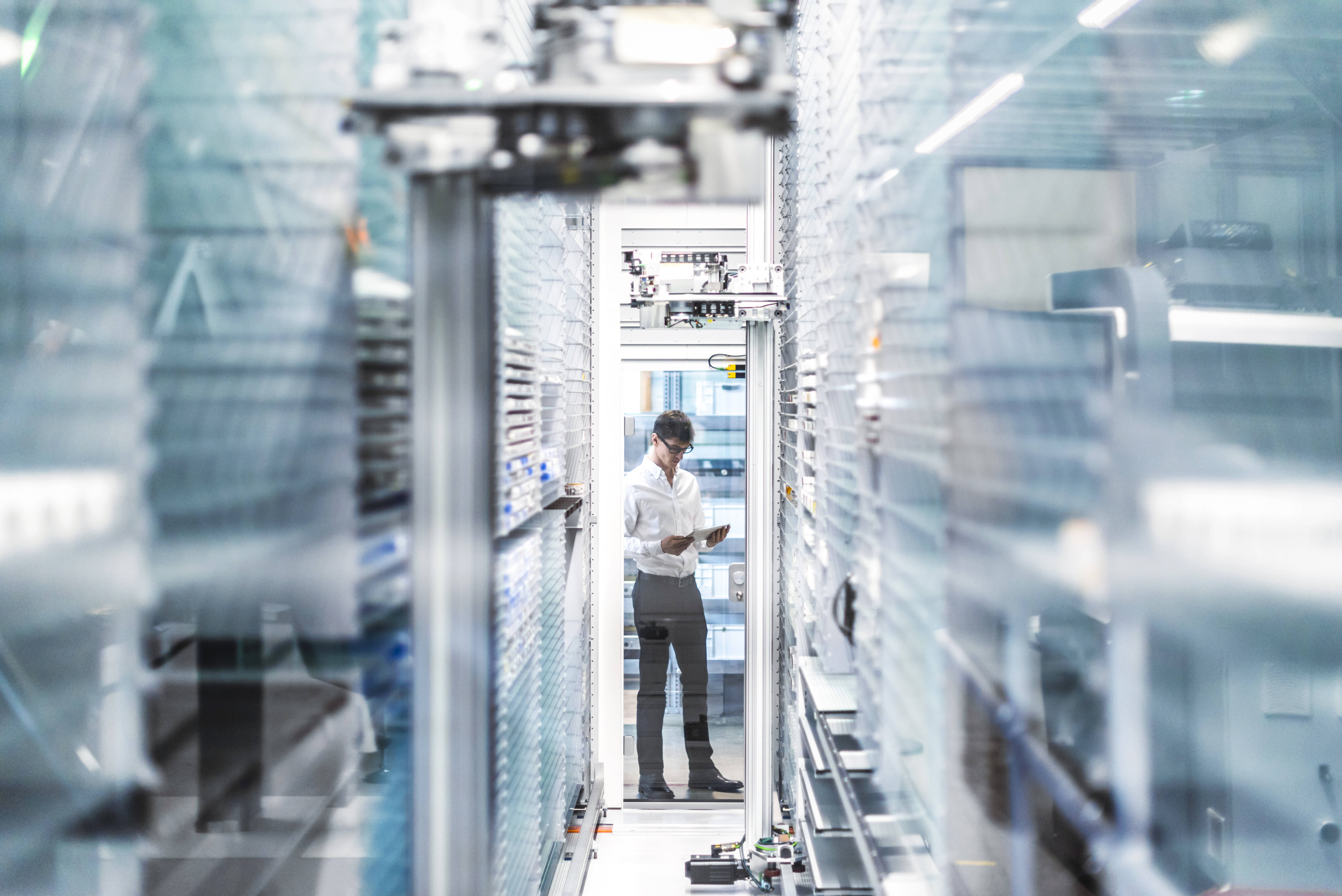 Ein Mann steht mit einem Tablet am Ende eines Ganges in einem Serverraum