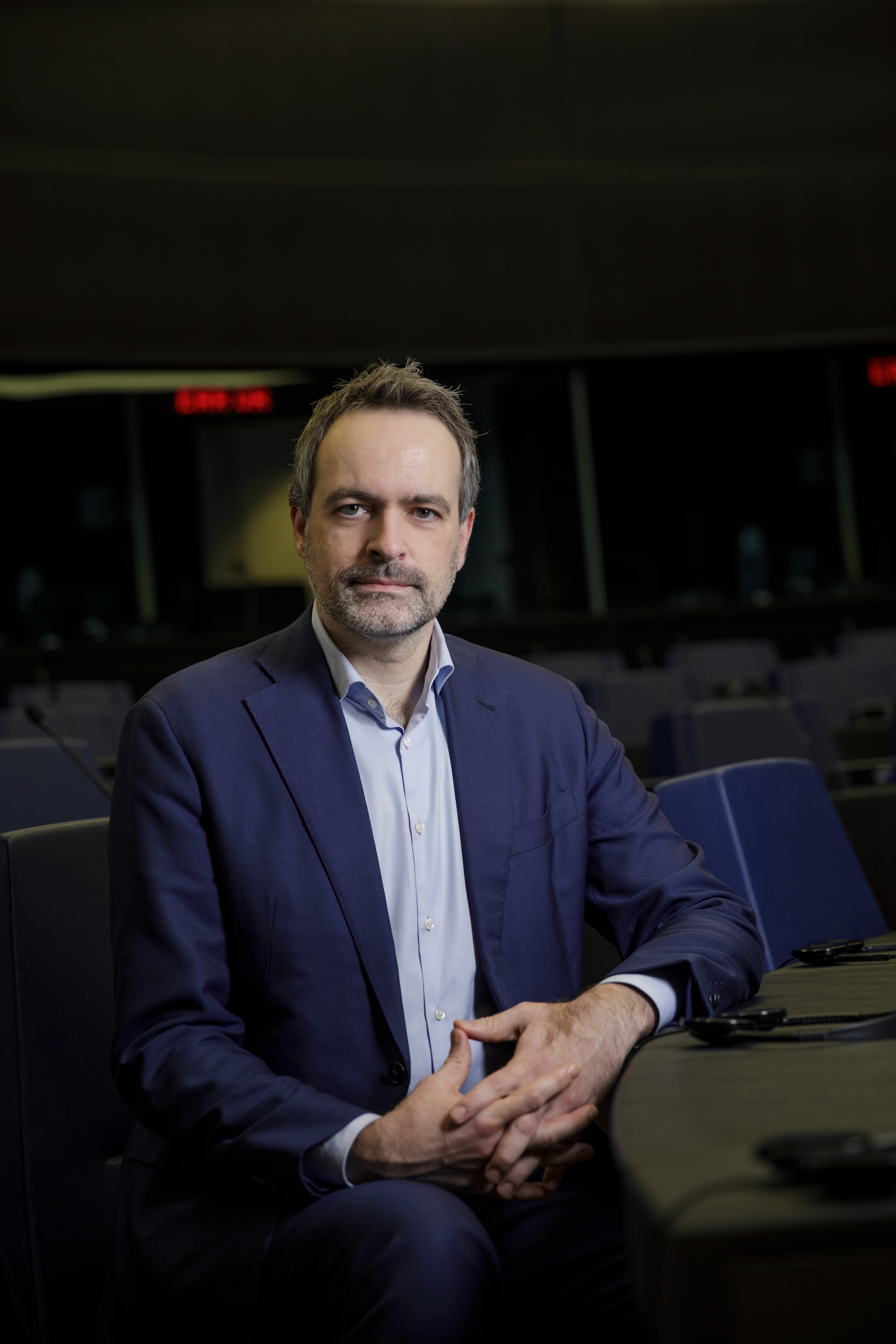 Porträt von René Repasi, sitzend am Tisch in einem Sitzungssaal