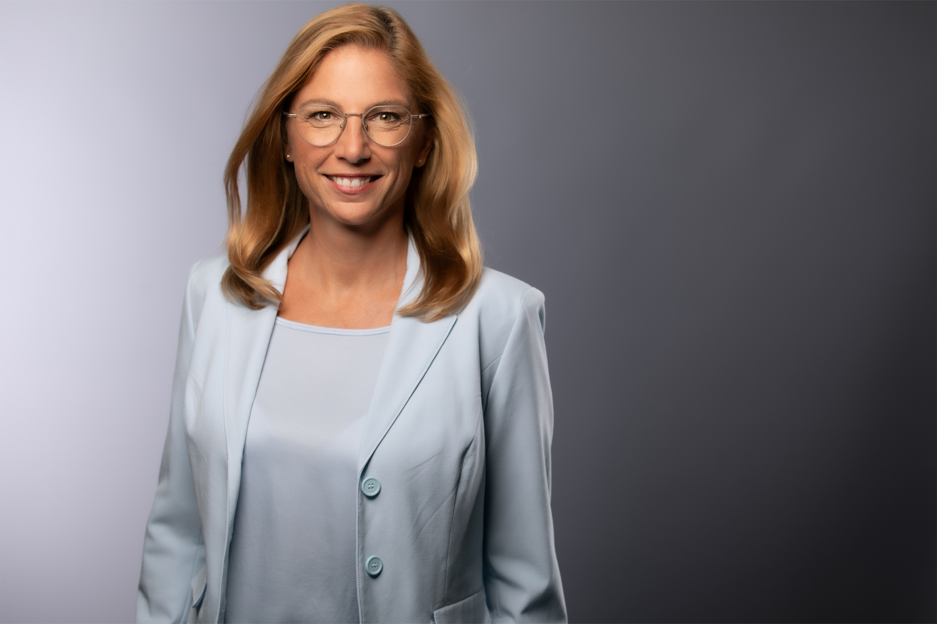 Porträt von Sabine Bätzing-Lichtenthäler im grauen Sakko vor grauem Hintergrund