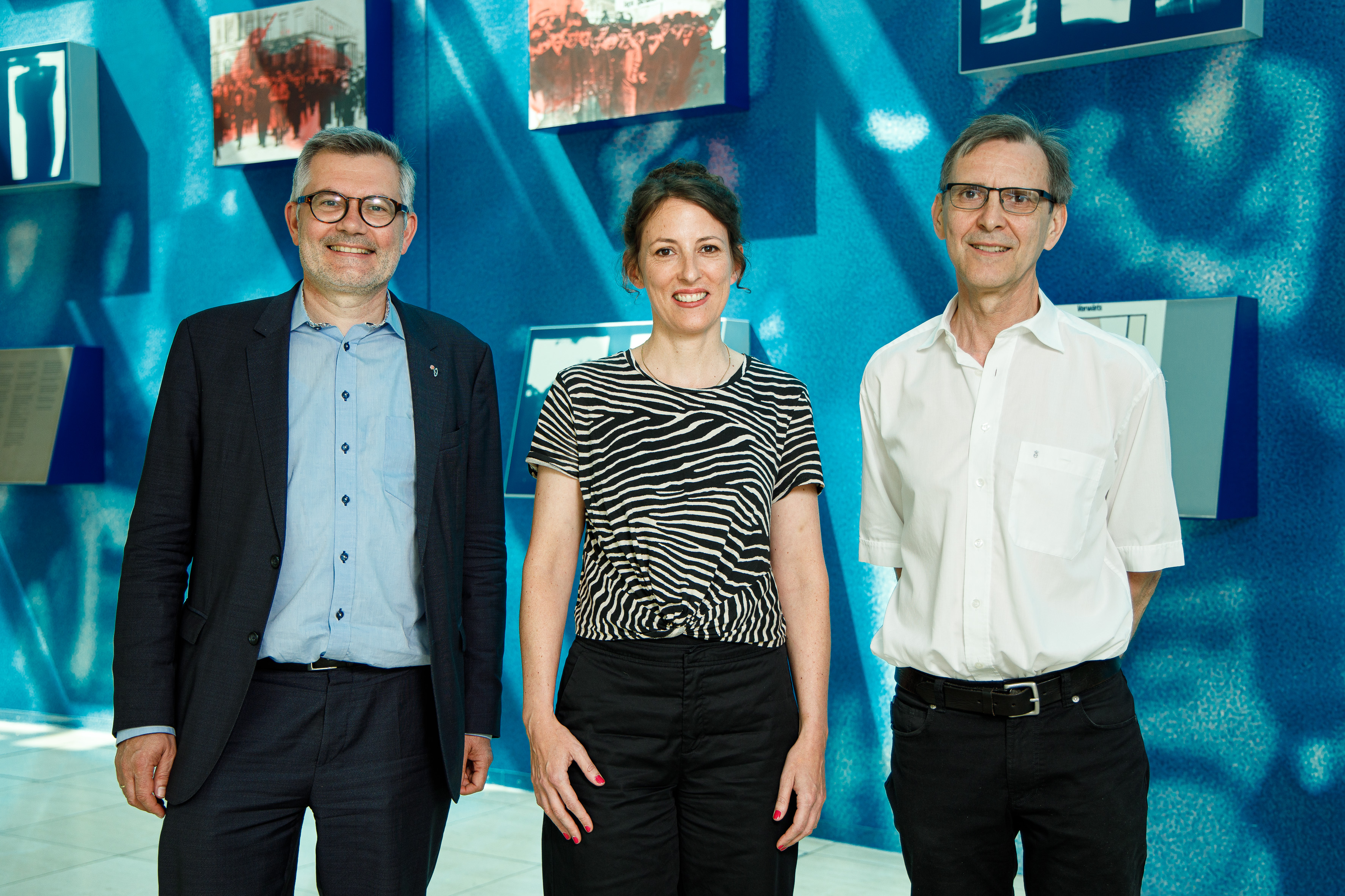 Vor der blauen Historienwand im Willy-Brandt-Haus: Der SPD-Geschichtsbeauftragte Nietmatr Nietan (l) mit den beiden neuen Sprechern des SPD-Geschichtsforums Kristina Meyer (m) und Bernd Rother (r)