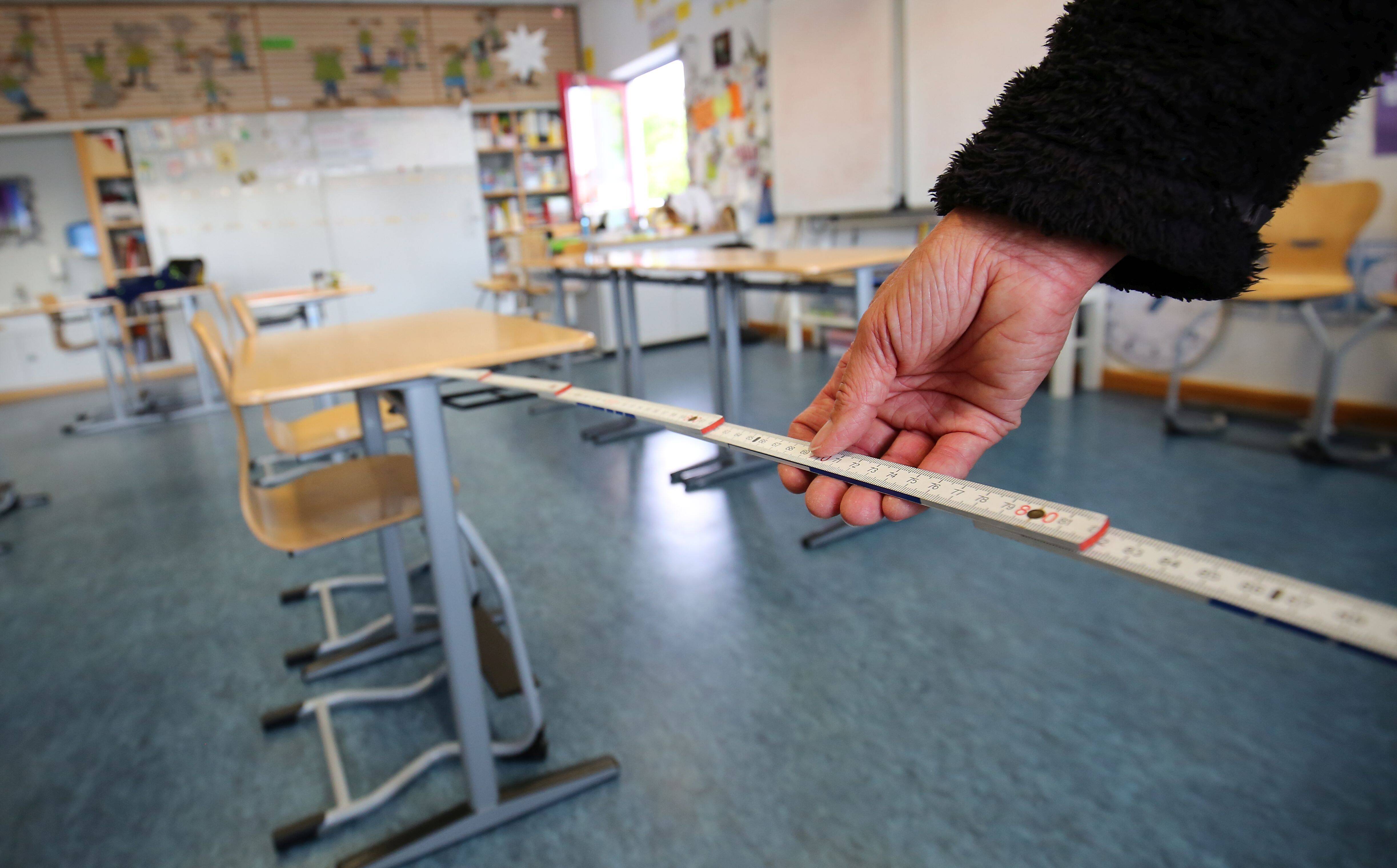 In einer Schule werden die Abstände zwischen den einzelnen Sitzplätzen ausgemessen.