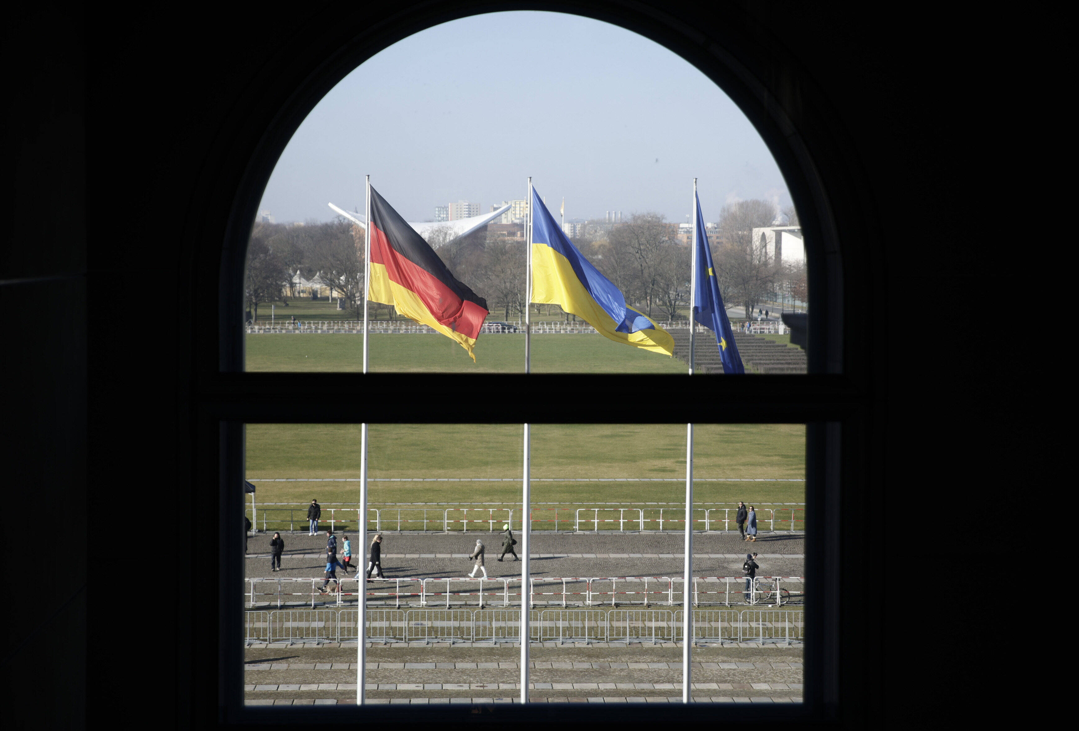 Deutsche, ukrainische und europäische Fahne vor dem Reichstagsgebäude: Wie wirkt sich die Zeitenwende des russischen Kriegs auf die deutsche Außenpolitik aus?