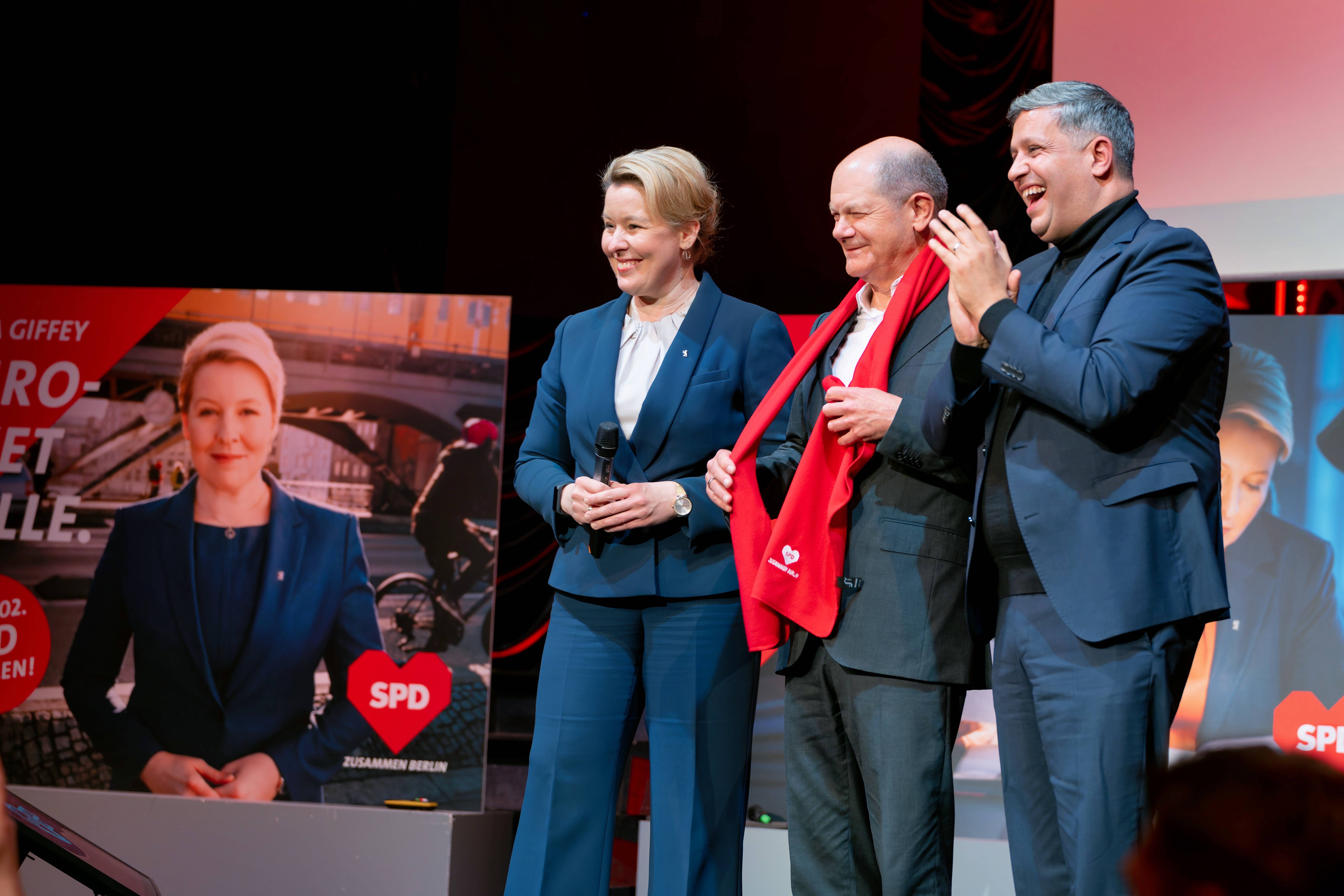 Das passende Kleidungsstück zum Winter-Wahlkampf: Berlins Regierende Bürgermeisterin Franziska Giffey (l.) und SPD-Landesvorsitzender Raed Saleh (r.) schenken Bundeskanzler Olaf Scholz einen roten Schal mit dem Motto "Zusammen Berlin".