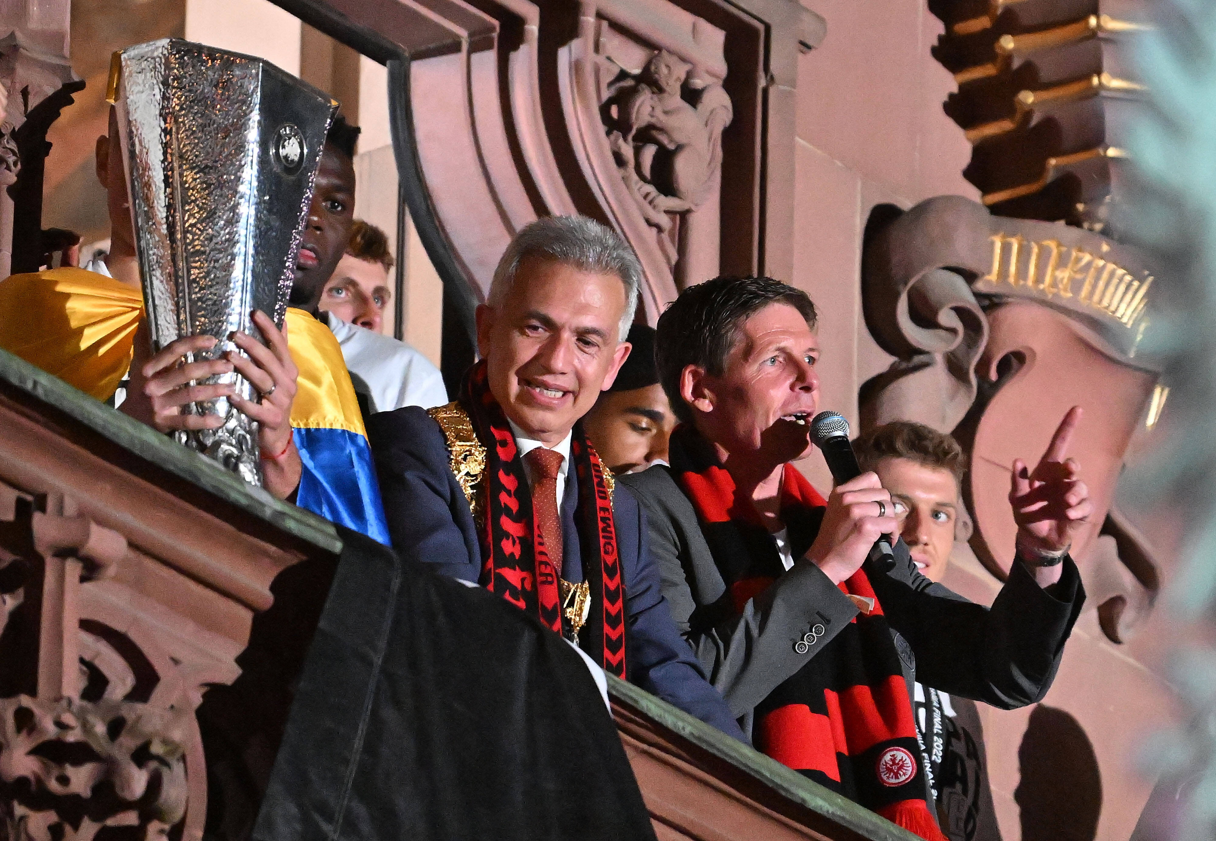Eintracht-Trainer Oliver Glasner hält auf dem Frankfurter Rathausbalkon eine Ansprache nach dem Europapokalgewinn. Oberbürgermeister Peter Feldmann steht daneben und kann sich kaum von der Trophäe trennen, obwohl sein Anteil am Gewinn doch eher gering war.