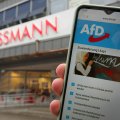 Handy mit der Internetseite der AfD vor einer Rossmann-Filiale