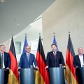 Gunnar Groebler, Friedrich Merz, Lars Klingbeil und Jürgen Kerner an Redepulten vor Deutschland- und Europafahnen