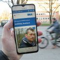 Fahndungswebsite auf einem Smartphone, im Hintergrund eine verschwommener Radfahrer