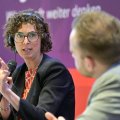 Die Ökonomin Clara Mattei mit Mikrofon gestikulierend im Gespräch